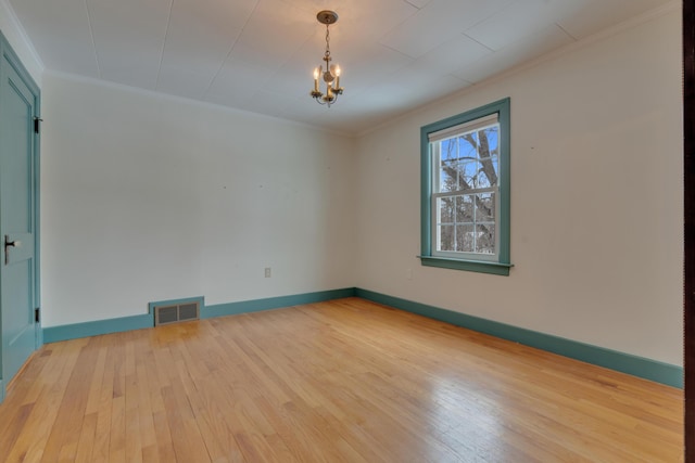 empty room with wood-type flooring, visible vents, crown molding, and an inviting chandelier