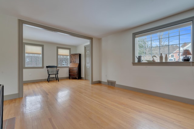 unfurnished living room featuring baseboards, visible vents, and light wood-style floors