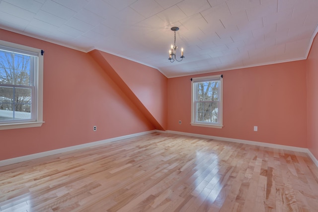 additional living space featuring light wood-style floors, baseboards, and a notable chandelier