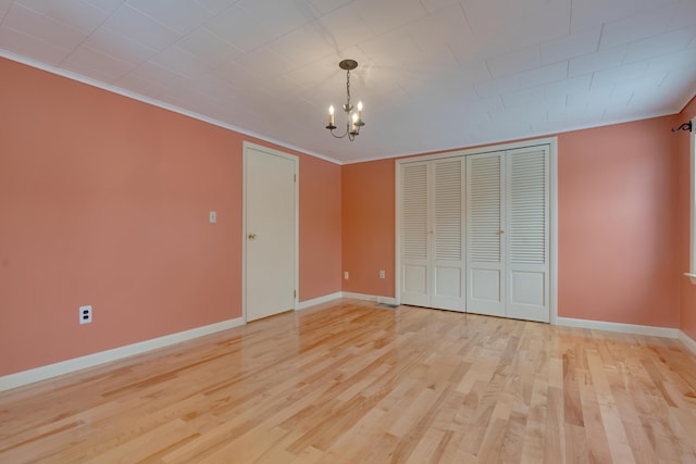 unfurnished bedroom featuring an inviting chandelier, ornamental molding, and light wood-style floors