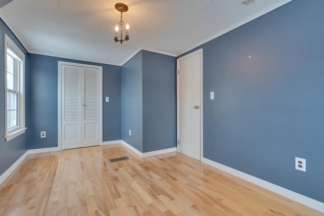 unfurnished bedroom featuring light wood-type flooring, a closet, crown molding, and baseboards