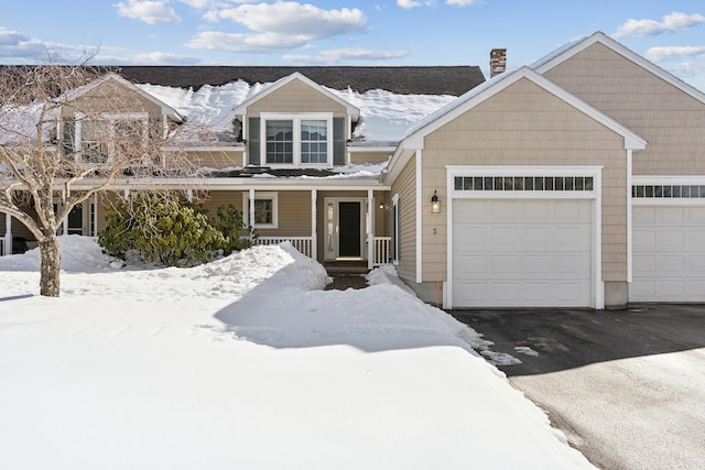 view of front of house with a garage, aphalt driveway, a chimney, and covered porch