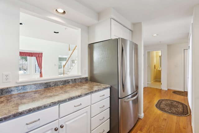 kitchen with light wood finished floors, recessed lighting, freestanding refrigerator, white cabinetry, and baseboards