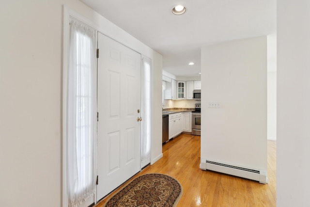 foyer entrance featuring light wood-type flooring, a baseboard radiator, and recessed lighting