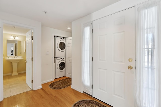 foyer featuring light wood finished floors, stacked washer and clothes dryer, and baseboards