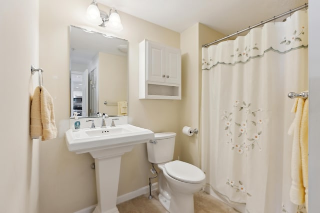 bathroom with toilet, a shower with curtain, baseboards, and a sink