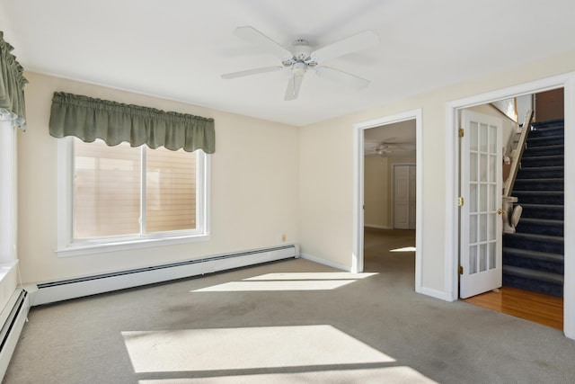 spare room featuring stairway, baseboard heating, carpet, and baseboards