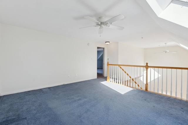 spare room with lofted ceiling with skylight, carpet flooring, ceiling fan, and baseboards