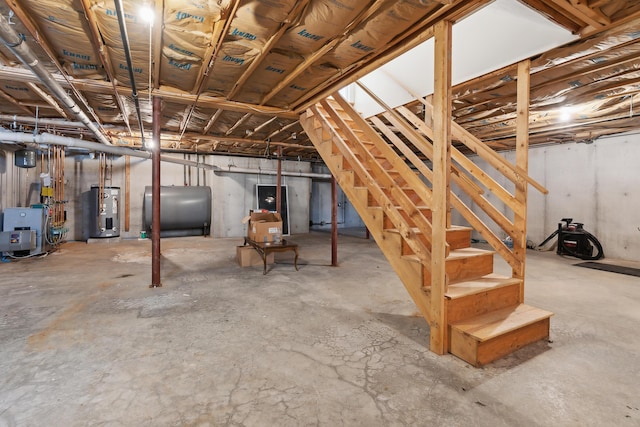 unfinished below grade area featuring heating fuel, stairs, water heater, and a heating unit