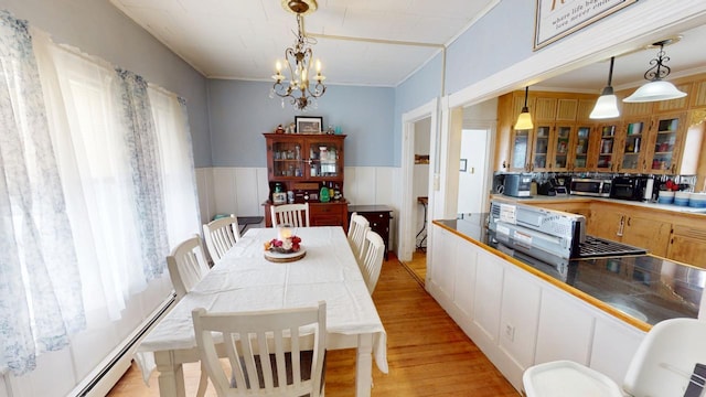 dining space with a wainscoted wall, crown molding, baseboard heating, an inviting chandelier, and light wood-style floors