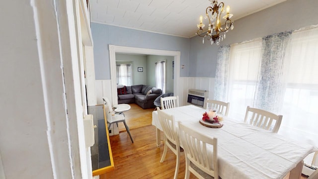 dining room with heating unit, a wainscoted wall, light wood-style floors, and a glass covered fireplace