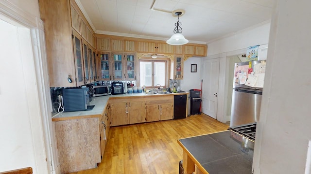 kitchen with light wood-style flooring, stainless steel appliances, a sink, glass insert cabinets, and crown molding