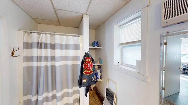 bathroom with curtained shower, a drop ceiling, and heating unit