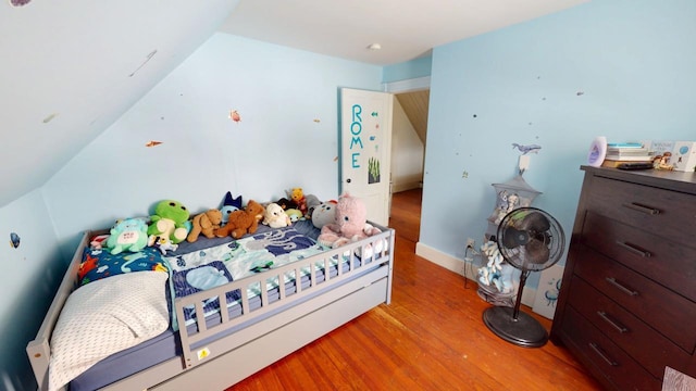 bedroom featuring lofted ceiling, baseboards, and wood finished floors