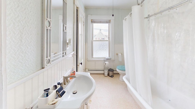 full bath featuring a textured wall, toilet, a wainscoted wall, a shower with shower curtain, and baseboard heating