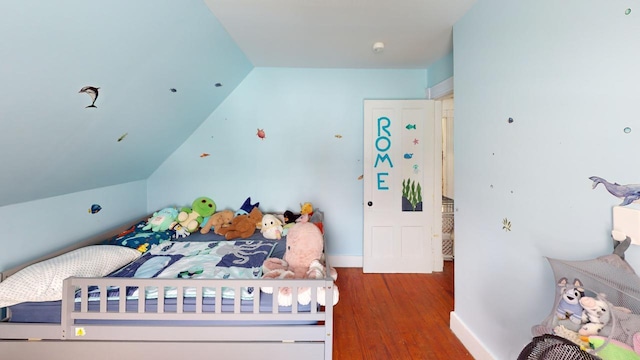 bedroom featuring lofted ceiling, baseboards, and wood finished floors