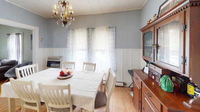 dining area with a notable chandelier, light wood-style floors, a healthy amount of sunlight, wainscoting, and heating unit