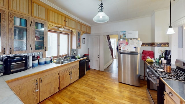 kitchen with a sink, light wood-style floors, ornamental molding, appliances with stainless steel finishes, and tile counters