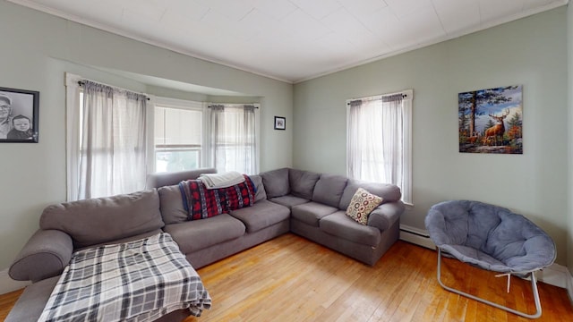 living room featuring a baseboard heating unit, plenty of natural light, light wood-style flooring, and crown molding