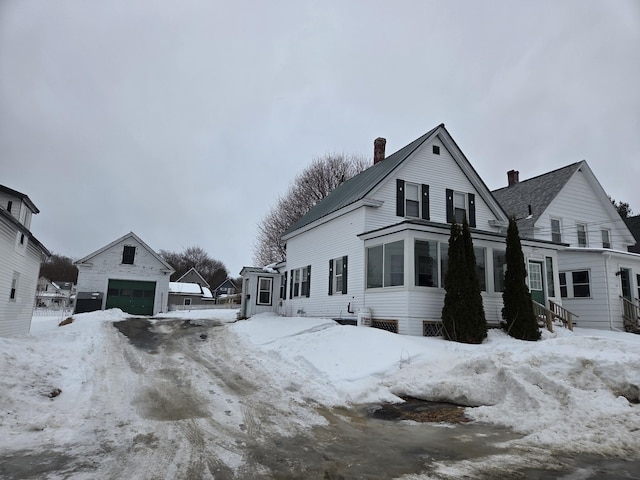 view of snow covered exterior featuring a detached garage and an outdoor structure