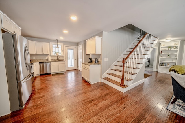 kitchen with open floor plan, stainless steel appliances, light wood finished floors, and white cabinetry