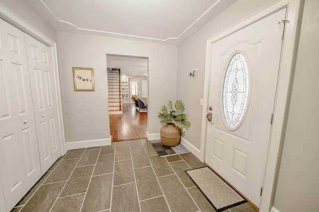 foyer with dark wood-style floors, stairway, and baseboards