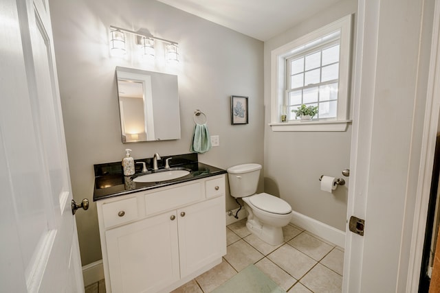 half bathroom with baseboards, vanity, toilet, and tile patterned floors