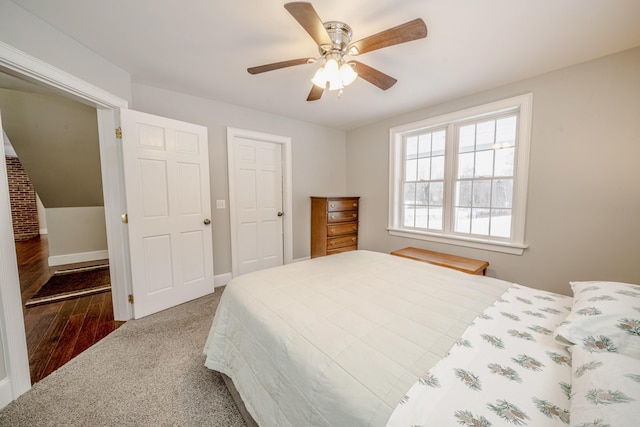 carpeted bedroom with wood finished floors, a ceiling fan, and baseboards