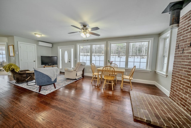 dining room featuring dark wood-style flooring, a ceiling fan, baseboards, an AC wall unit, and a wood stove