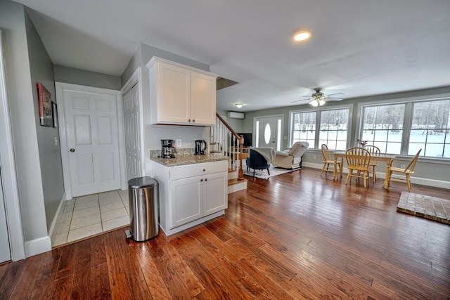 kitchen with baseboards, ceiling fan, light stone counters, wood finished floors, and white cabinetry