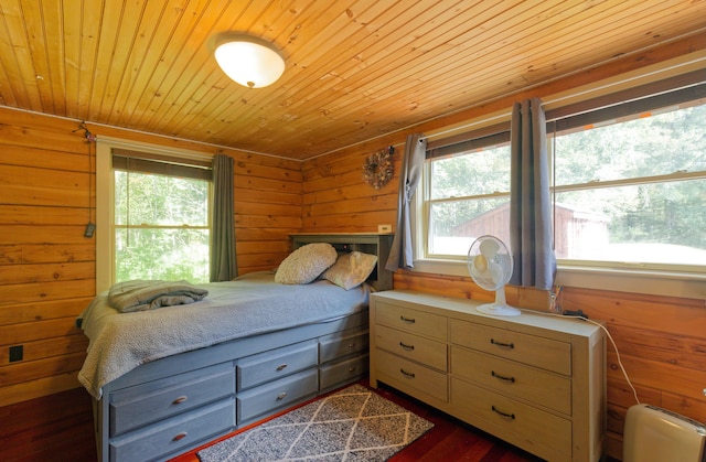 bedroom with dark wood-style floors, wooden ceiling, and wood walls