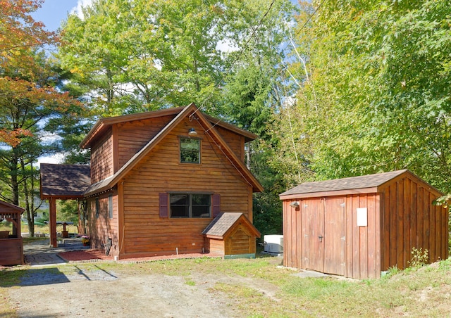 exterior space with a shed, a shingled roof, and an outbuilding