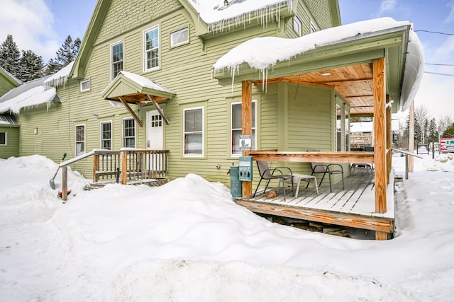 snow covered house featuring a wooden deck