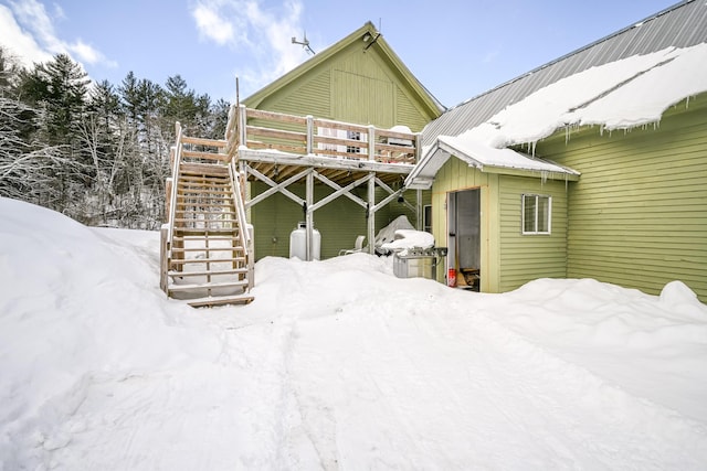 snow covered house featuring stairs and a deck