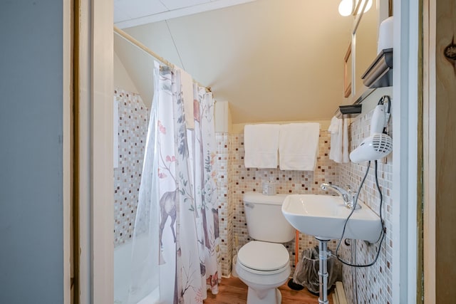 bathroom with toilet, a sink, tile walls, and wood finished floors