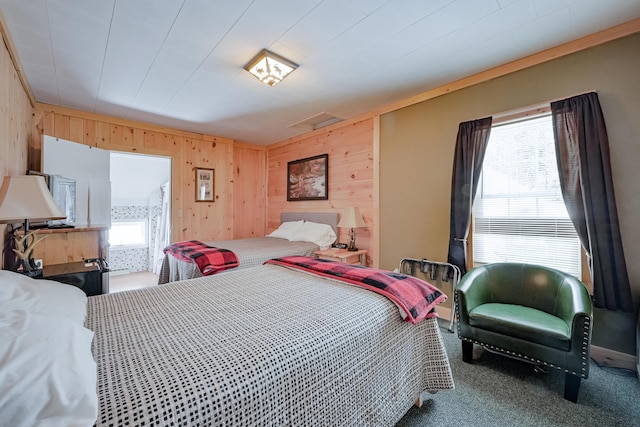 bedroom with carpet floors, attic access, and wooden walls