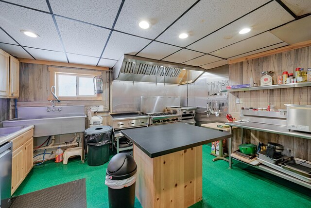 kitchen with dishwasher, wooden walls, carpet flooring, and light brown cabinets