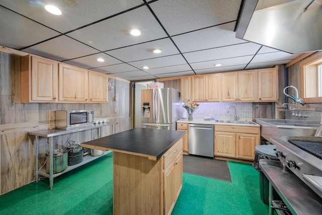 kitchen with stainless steel appliances, decorative backsplash, light brown cabinets, a sink, and a kitchen island