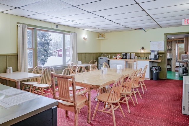 dining area featuring a paneled ceiling, wainscoting, and carpet