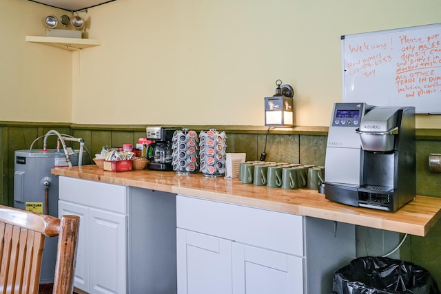 kitchen with a wainscoted wall, butcher block countertops, white cabinets, water heater, and open shelves