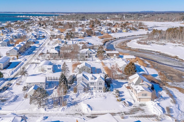 snowy aerial view featuring a water view and a residential view