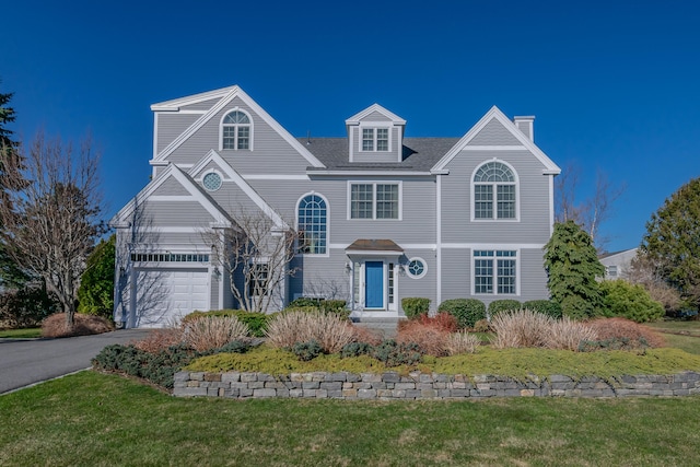 view of front of home with a front lawn, driveway, a chimney, and a garage
