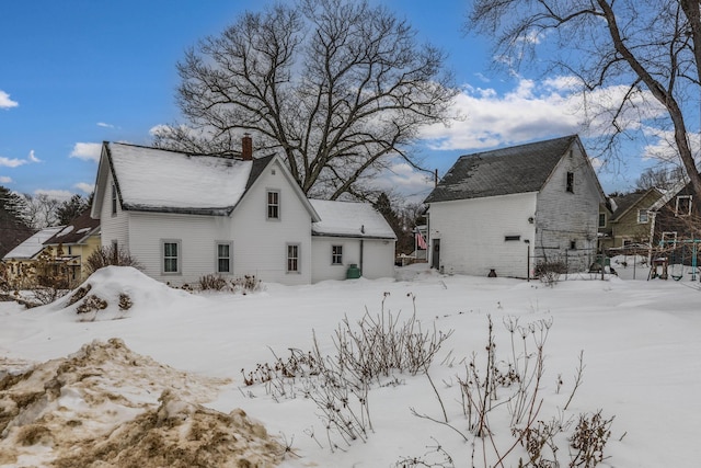 snow covered back of property with a chimney