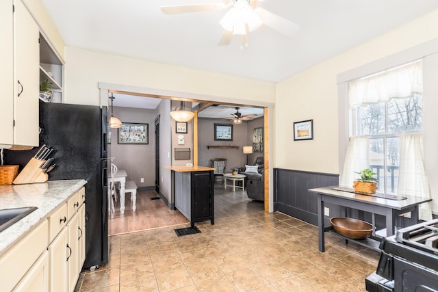 kitchen with wainscoting, light countertops, ceiling fan, and light tile patterned floors