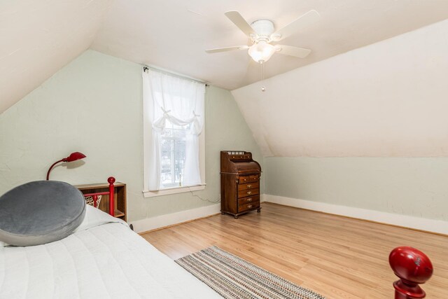 bedroom with vaulted ceiling, ceiling fan, light wood-style flooring, and baseboards