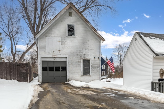 view of snowy exterior with a garage and fence