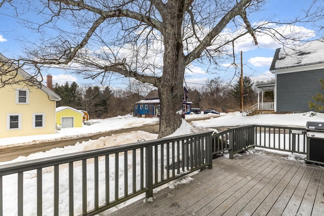 snow covered deck featuring grilling area, an outdoor structure, and a detached garage