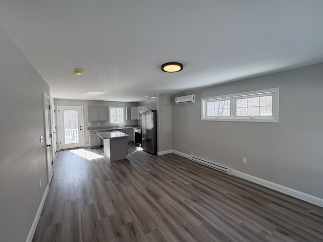 kitchen featuring baseboards, a baseboard radiator, freestanding refrigerator, an AC wall unit, and gray cabinetry