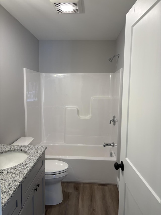 full bath featuring visible vents, toilet, wood finished floors,  shower combination, and vanity