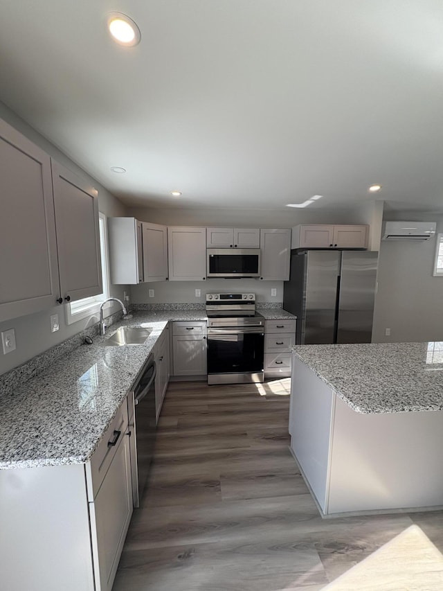 kitchen with light stone counters, appliances with stainless steel finishes, gray cabinets, and a sink